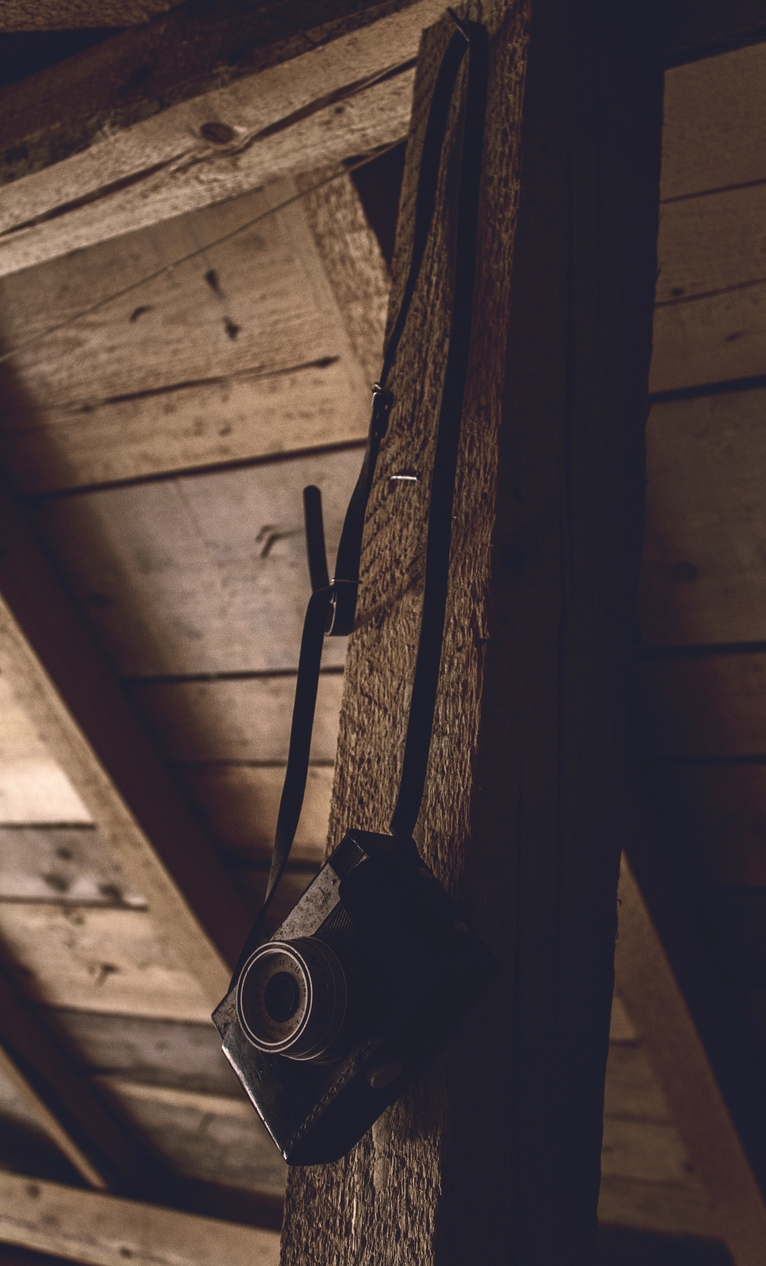 black point-and-shoot camera hanging on a brown wooden bar